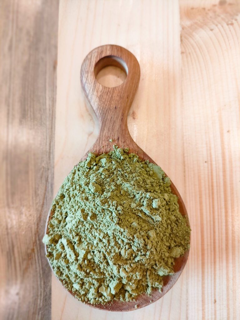 Green Kratom powder on a wooden spoon